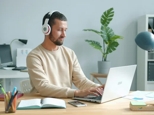 Uczestnik kursu w słuchawkach ogląda lekcję na laptopie